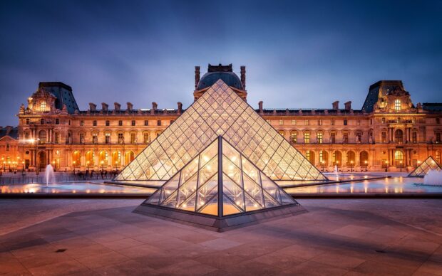 The Louvre glass pyramid illuminated at dusk in Paris France