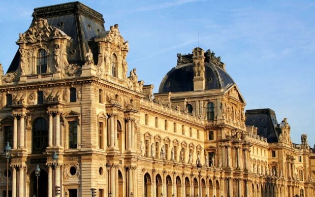 Historic Louvre architecture with detailed sculptures in bright sunlight