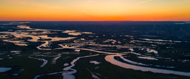 The Mississippi River reflects vibrant sunset colors over winding water paths, 4K Desktop Wallpaper