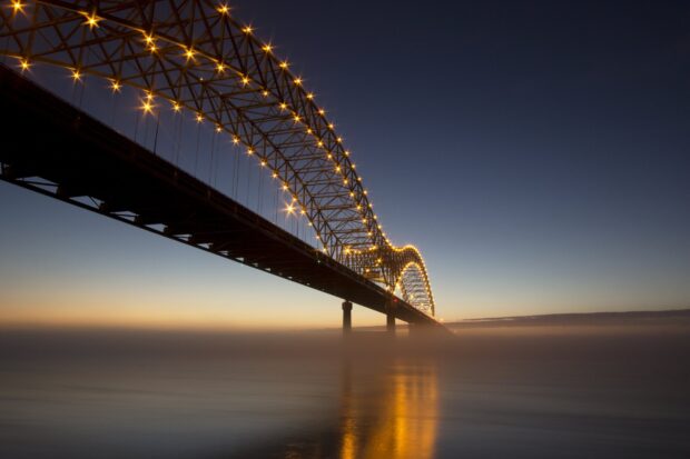 The Mississippi River is shown with a lit bridge extending over calm water at twilight, HD Desktop Wallpaper