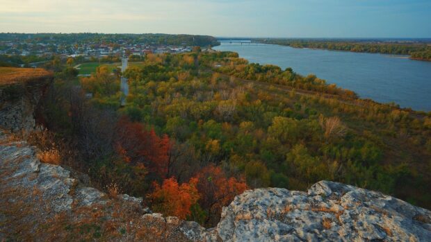 A scenic view of the Mississippi River flowing past rocky cliffs and colorful trees in autumn, HD Desktop Wallpaper