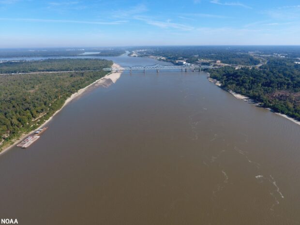 The Mississippi River flows under a steel bridge surrounded by green forests and clear sky, 2K Desktop Wallpaper