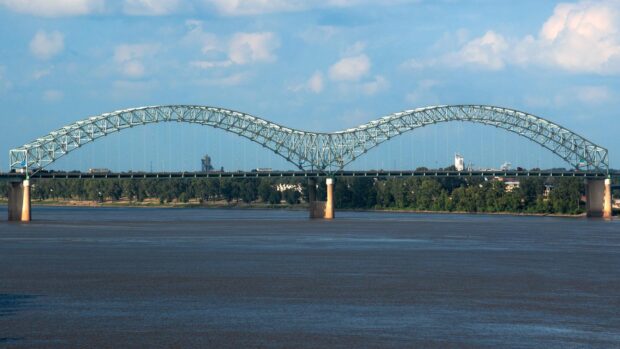 The Mississippi River features a steel arch bridge over calm water and a blue sky, HD Desktop Wallpaper
