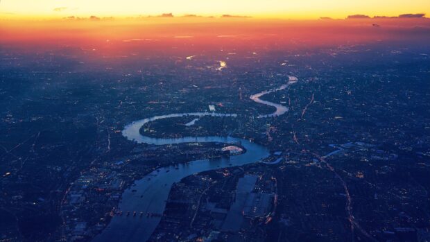 The River Thames flows through a cityscape illuminated by lights at dusk, 4K Desktop Wallpaper