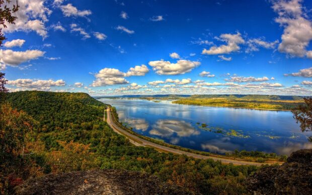 The Mississippi River flows through a landscape of green hills and a winding road under a vibrant sky, HD Wallpaper