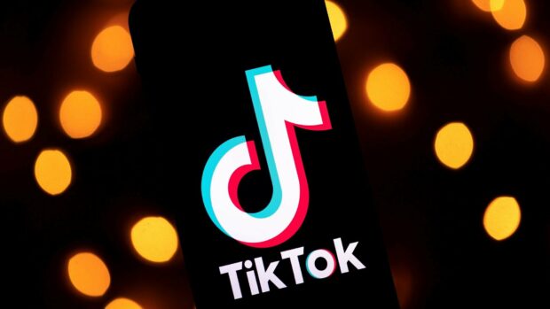 TikTok logo displayed on a mobile screen with glowing orange lights in the background