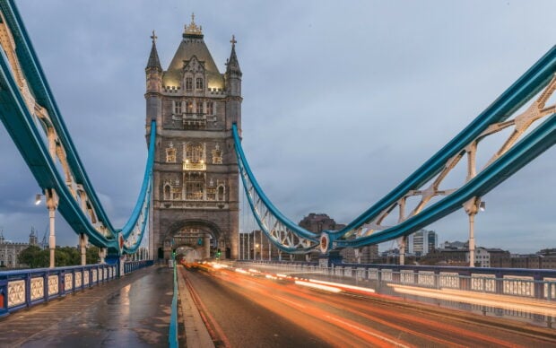 Tower Bridge in the United Kingdom shows light trails from passing cars during dusk, 2K Desktop Wallpaper