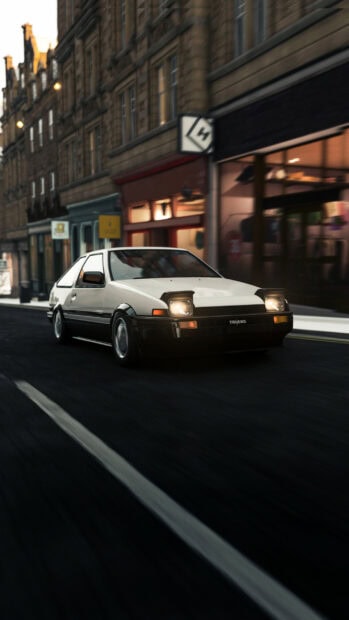 Classic white DeLorean DMC-12 sports car driving through city street at dusk.