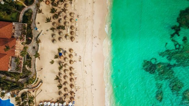 An aerial view of a tropical beach with clear turquoise water and sandy shore in the Dominican Republic, 2K Desktop Wallpaper