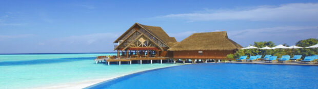 The tropical bungalow stands over clear blue ocean waters with a bright sky, 4K Desktop Wallpaper