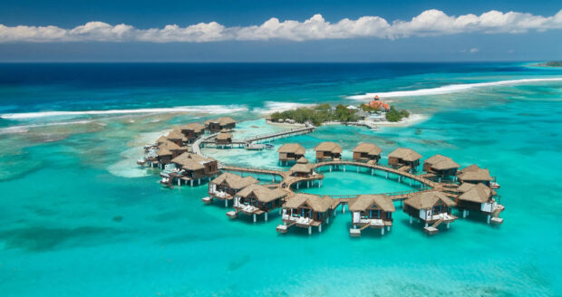 Aerial view of bungalow houses over turquoise water under a bright sky, HD Desktop Wallpaper