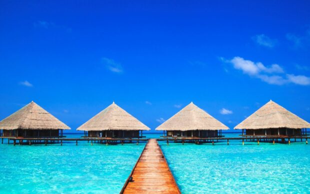 A wooden pier leads to tropical bungalows under a blue sky, HD Desktop Wallpaper