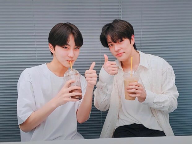 Two young men are drinking beverages and showing thumbs up in Enhypen Wallpapers