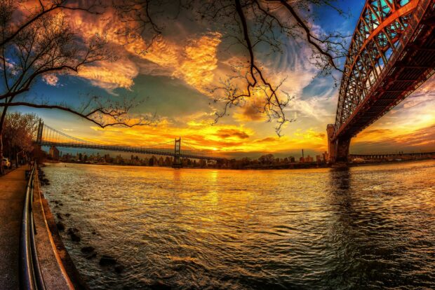 The vibrant sunset over the river framed by bridges and bare trees in United States