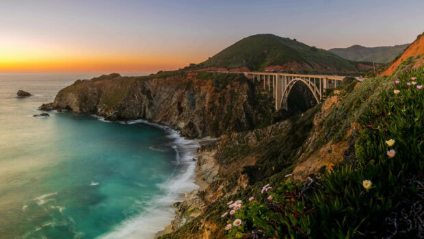 Scenic view of United States coastline with ocean cliffs and a large bridge at sunset