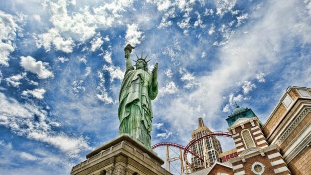 The United States Liberty statue stands tall under a vibrant sky with iconic cityscape in the background