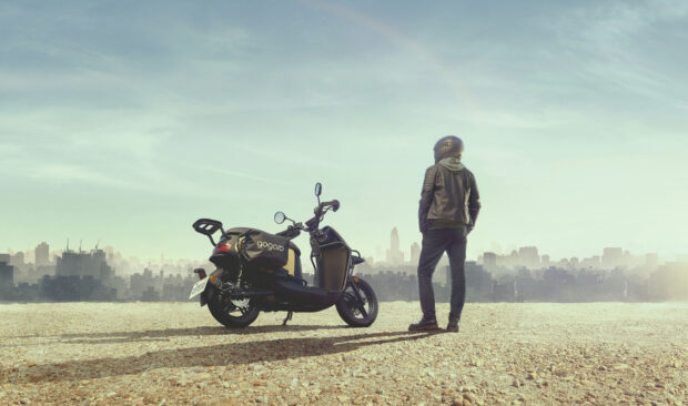 A man wearing a helmet stands next to a black scooter overlooking the cityscape, 2K Desktop Wallpaper