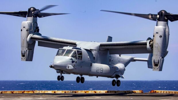 V 22 Osprey aircraft flying over the sea near the deck with clear sky in the background
