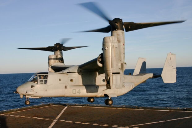 V 22 Osprey aircraft hovering above a ship deck over the ocean during daylight