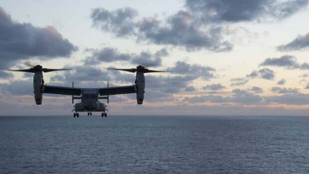 V 22 Osprey flying over the ocean at sunset with cloudy sky
