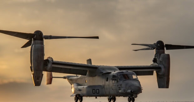 A close up view of a V 22 Osprey aircraft on the ground during sunset