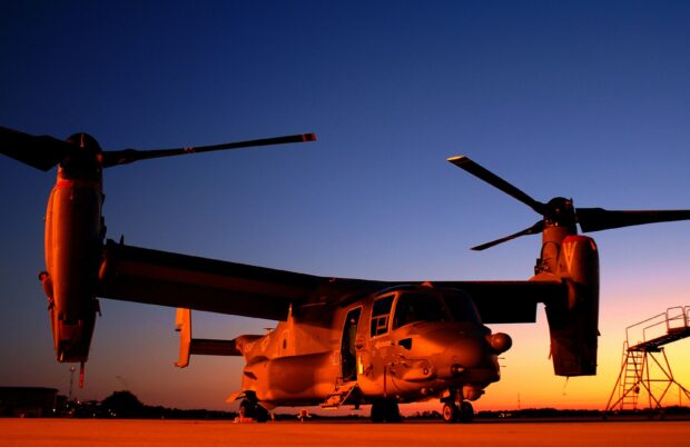 A V 22 Osprey aircraft parked on the runway during sunset with clear sky background