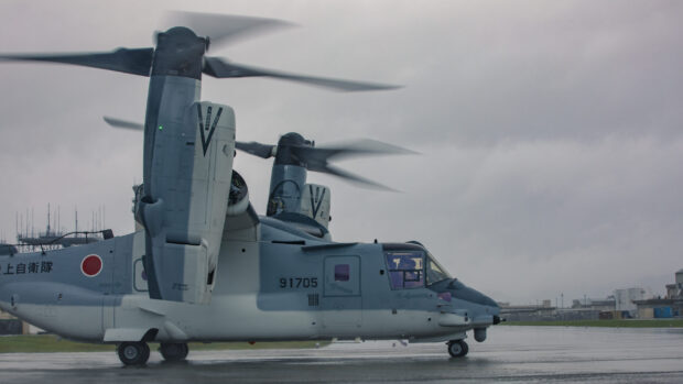 A V 22 Osprey tiltrotor aircraft preparing for takeoff on a wet runway