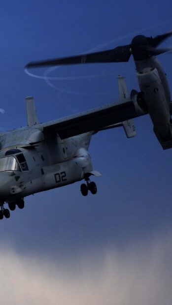 Military V 22 Osprey flying above clouds in clear sky