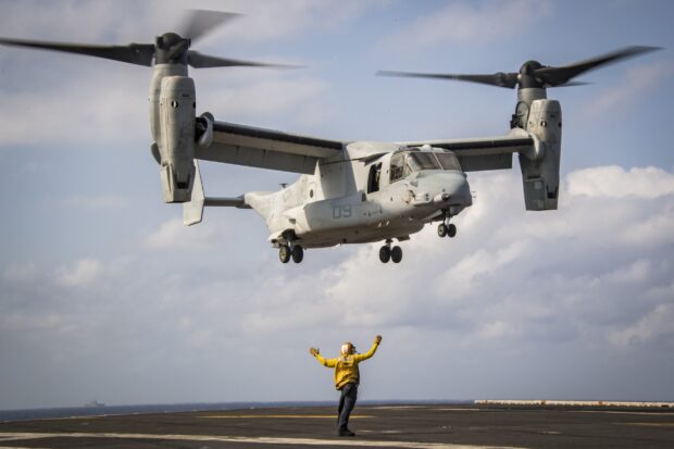 Person guiding V 22 Osprey aircraft on flight deck during landing