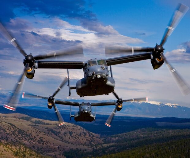 Two V 22 Osprey aircraft flying over mountainous terrain