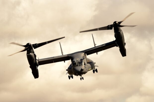 V 22 osprey flying in the sky with rotors spinning against cloudy background