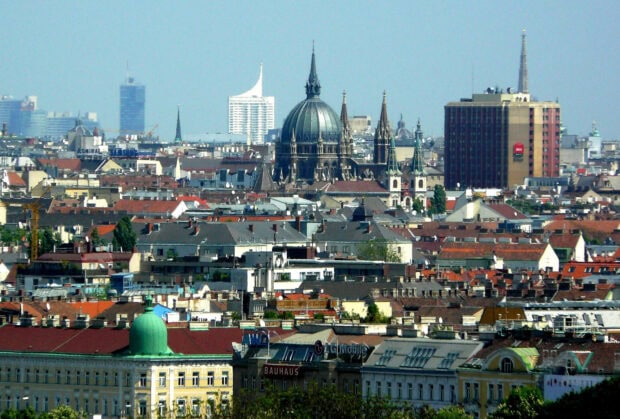 A panoramic view of Vienna Austria cityscape with historic rooftops and a large dome shaped cathedral in the center
