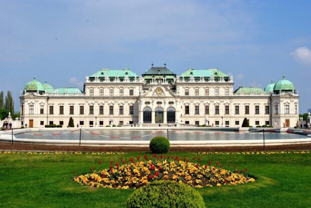 A historic palace in Vienna Austria surrounded by colorful flowers and greenery