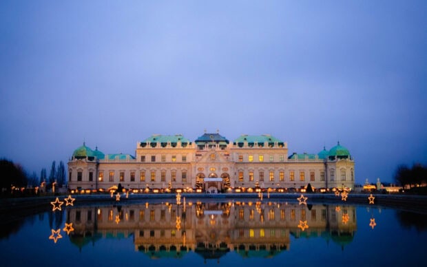 Vienna Austria with beautiful illuminated historic architecture reflecting in calm water at dusk