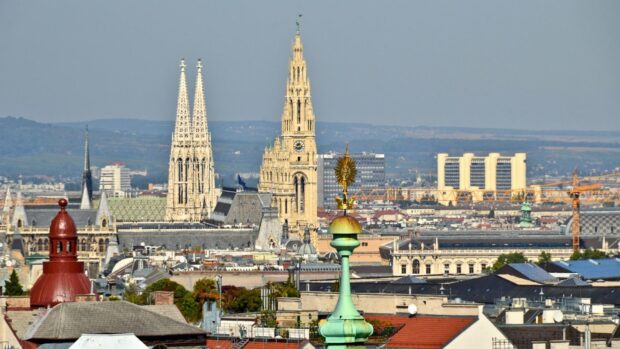 Historic cathedral towers in Vienna Austria cityscape with urban buildings and distant hills