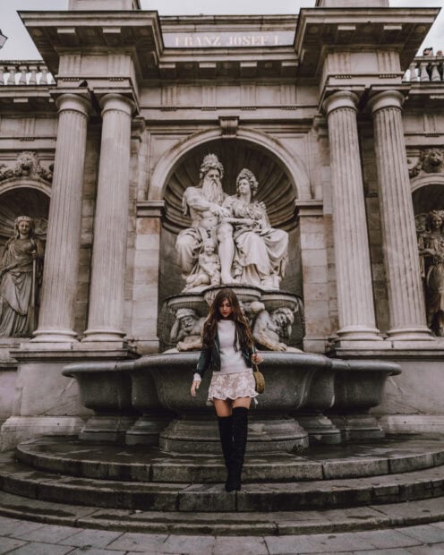 Young woman walking near a historic statue in Vienna Austria