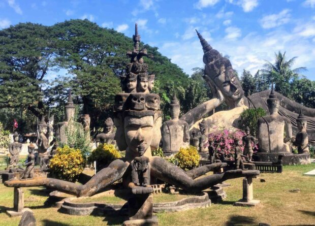 Ancient stone sculptures in Vientiane with serene faces and intricate details under clear blue sky