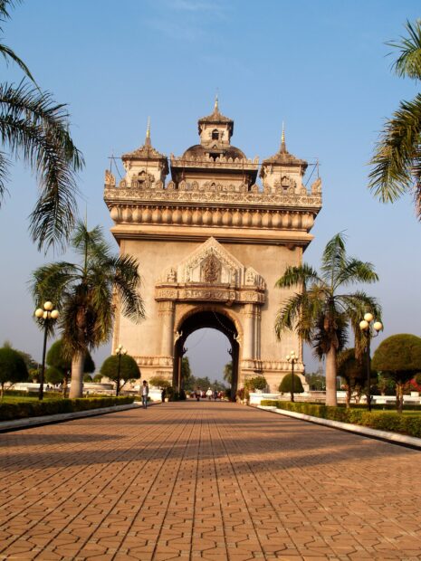 Famous Patuxai monument in Vientiane amid palm trees and clear sky