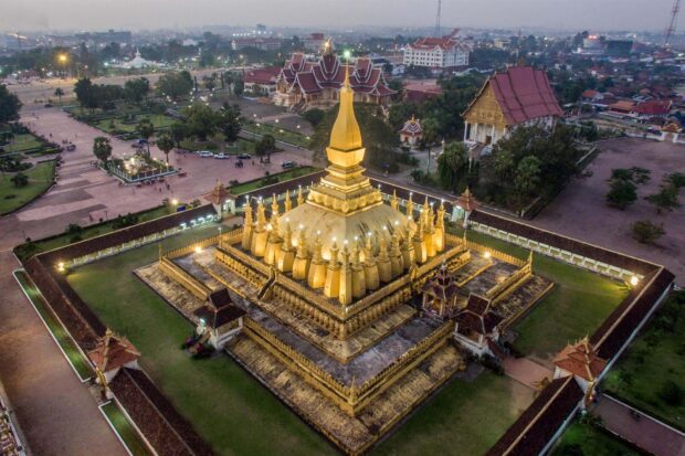 The golden stupa landmark in Vientiane with surrounding traditional buildings and cityscape