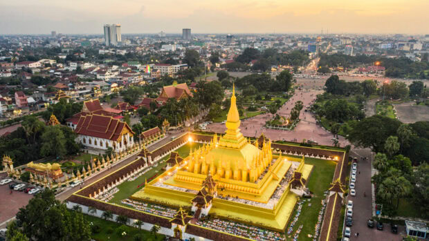 The golden stupa of Vientiane with cityscape in the background at sunset