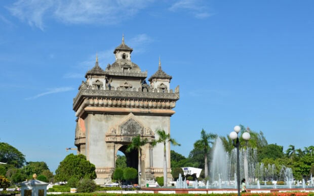 The iconic Vientiane monument surrounded by greenery and fountains under a clear blue sky