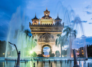 The Patuxai monument in Vientiane illuminated at dusk with water fountains in front