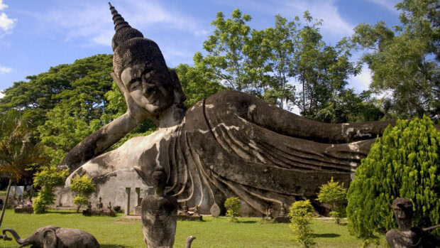 Reclining Buddha statue surrounded by greenery in Vientiane park