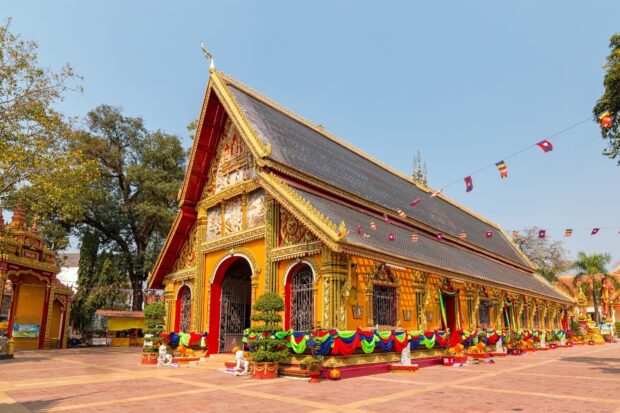 The ornate temple in Vientiane decorated with colorful flags and detailed carvings
