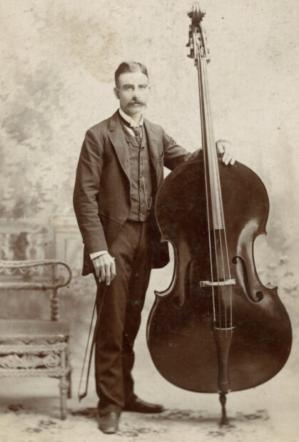 A vintage photograph of a man standing next to a double bass in an old studio, HD Desktop Wallpaper