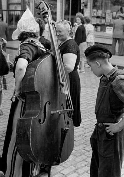 A boy and women are standing near a double bass in a black and white vintage street photo, HD PC Wallpaper