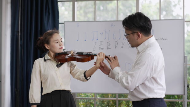 A woman practicing violin while her teacher helps with finger placement, 4K Desktop Wallpaper