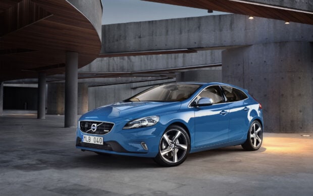 Blue Volvo car parked in a modern concrete building with wooden ceiling details