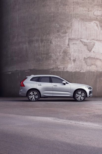 Silver Volvo car parked in front of a textured concrete wall with an urban setting