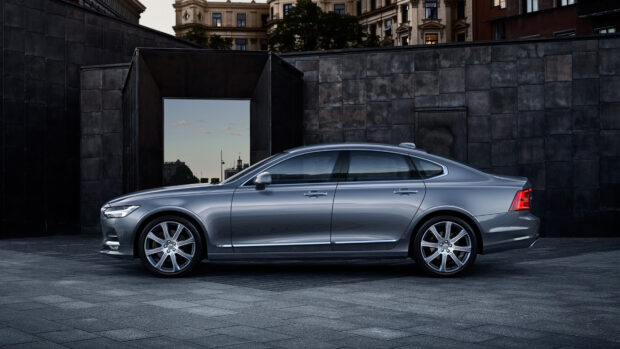 A sleek Volvo sedan parked in front of a modern dark stone architectural background